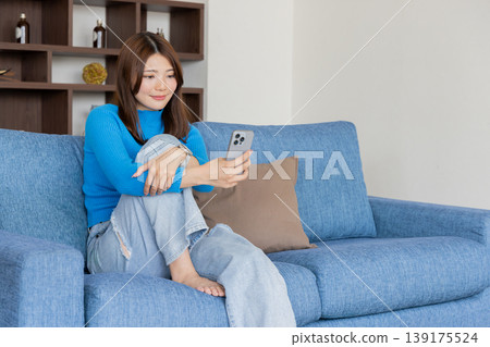 觀看在沙發的婦女一個智能手機 觀看在沙發的婦女一個智能手機 139175524