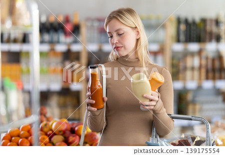 Young woman chooses sauces in grocery store Young woman chooses sauces in grocery store 139175554