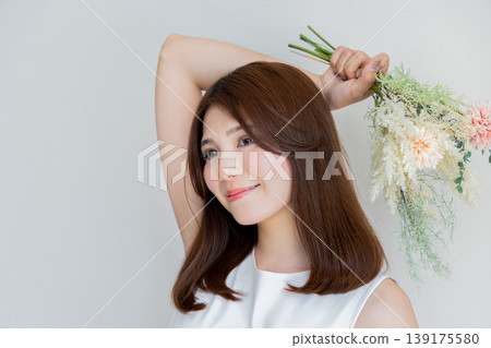 女子手持花朵、笑容自然的美麗肖像。 女子手持花朵、笑容自然的美麗肖像。 139175580