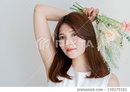 女子手持花朵、笑容自然的美麗肖像。 女子手持花朵、笑容自然的美麗肖像。 139175581