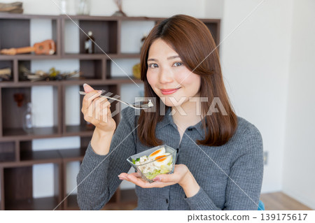 一位注重健康的女性喜歡在家享用沙拉。 一位注重健康的女性喜歡在家享用沙拉。 139175617