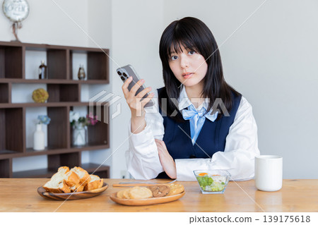 一位身穿制服的女士在早餐時查看智慧型手機:這就是她的生活方式。 一位身穿制服的女士在早餐時查看智慧型手機:這就是她的生活方式。 139175618