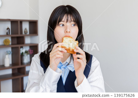 A young woman in a uniform eating bread for breakfast - Natural lifestyle A young woman in a uniform eating bread for breakfast - Natural lifestyle 139175626