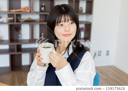 A female student in uniform drinking coffee - a relaxed morning moment. A female student in uniform drinking coffee - a relaxed morning moment. 139175628