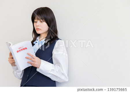 Female student contemplating with a textbook in hand - Image of studying and taking entrance exams (copy space available) 139175665