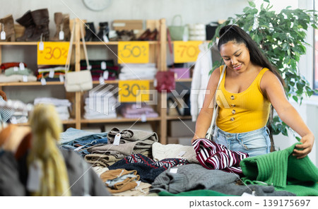 Happy young girl choosing sweater in clothing store 139175697