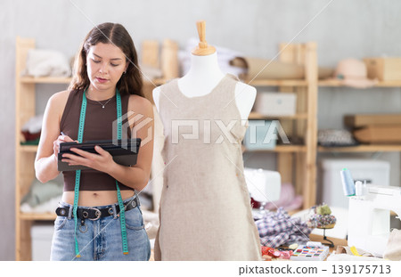 Female fashion designer drawing clothing on tablet in studio Female fashion designer drawing clothing on tablet in studio 139175713