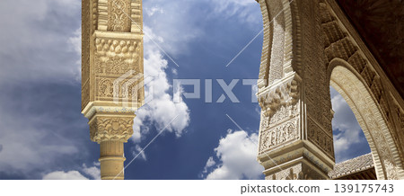 Arches in Islamic (Moorish) style (against the background of a beautiful sky with clouds) in Alhambra, Granada, Spain Arches in Islamic (Moorish) style (against the background of a beautiful sky with clouds) in Alhambra, Granada, Spain 139175743