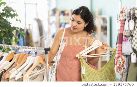 Selective young girl choosing summer dresses or tops in clothing store Selective young girl choosing summer dresses or tops in clothing store 139175760