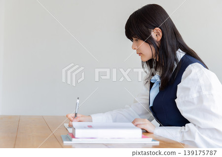 一位女學生正在筆記本上寫字,展現了她學習的場景。 一位女學生正在筆記本上寫字,展現了她學習的場景。 139175787