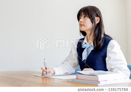 Portrait of a female student studying (notebook and textbook) 139175789