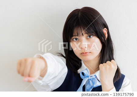 一幅女學生用有力地向前揮出的拳頭表達挑戰的肖像。 一幅女學生用有力地向前揮出的拳頭表達挑戰的肖像。 139175790