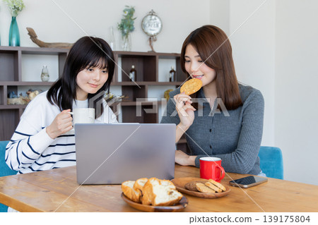 兩名女性在家用電腦工作時一邊吃零食——輕鬆的時刻。 139175804