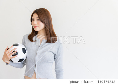 年輕女子手持足球的肖像，象徵運動和健康。 139175838