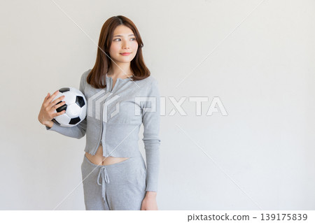 年輕女子手持足球的肖像，象徵運動和健康。 139175839