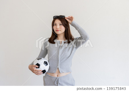 年輕女子手持足球的肖像，象徵運動和健康。 139175843