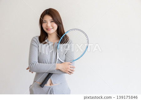 一位年輕女子手持網球拍-展現了一種運動健康的生活方式。 一位年輕女子手持網球拍-展現了一種運動健康的生活方式。 139175846
