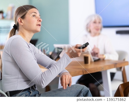 Two female colleagues are watching presentation in office room. Two female colleagues are watching presentation in office room. 139175862
