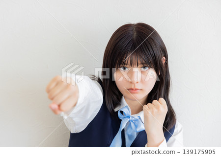 A portrait of a female student expressing her challenge with a powerful, forward-thrusting fist. A portrait of a female student expressing her challenge with a powerful, forward-thrusting fist. 139175905