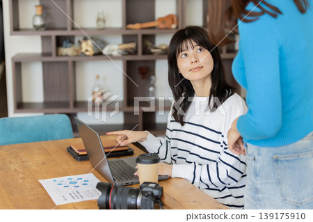 A woman working on her laptop during a meeting; a scene of communication in a shared office space. A woman working on her laptop during a meeting; a scene of communication in a shared office space. 139175910