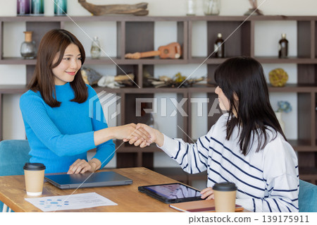 兩位年輕女性在商務場合握手,象徵合作與成功。 兩位年輕女性在商務場合握手,象徵合作與成功。 139175911