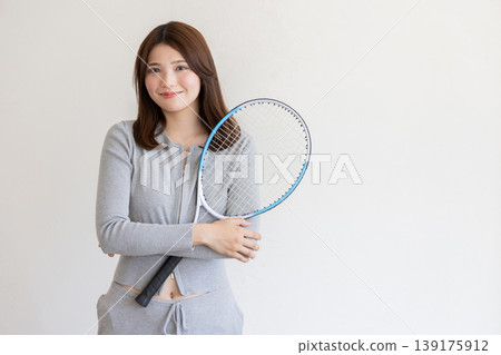 A young woman holding a tennis racket – an image of a sporty and healthy lifestyle. A young woman holding a tennis racket – an image of a sporty and healthy lifestyle. 139175912