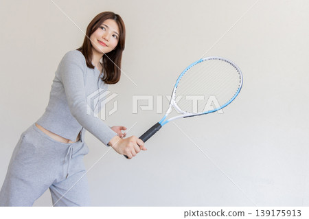 A young woman holding a tennis racket – an active and healthy sports image. A young woman holding a tennis racket – an active and healthy sports image. 139175913