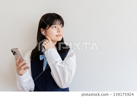 A high school girl wearing earphones and using her smartphone - Digital life and learning image A high school girl wearing earphones and using her smartphone - Digital life and learning image 139175924