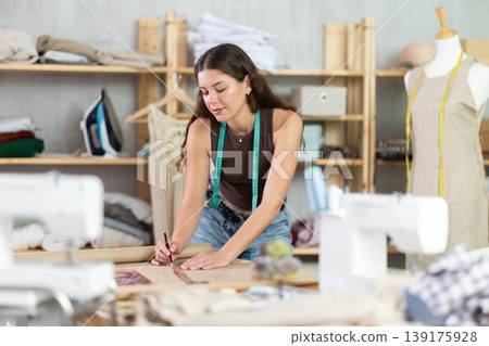 Woman tailor drawing on brown paper in workshop Woman tailor drawing on brown paper in workshop 139175928