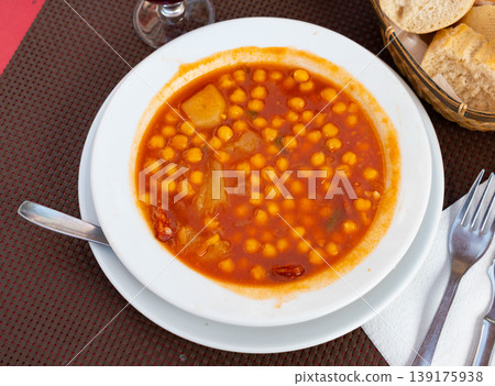 Delicious chickpeas cooked with pieces of chorizo sausage and bacon, onions, garlic, tomatoes, sweet paprika and spices served at plate for dinner. Spanish cuisine Garbanzos con chorizo Delicious chickpeas cooked with pieces of chorizo sausage and bacon, onions, garlic, tomatoes, sweet paprika and spices served at plate for dinner. Spanish cuisine Garbanzos con chorizo 139175938