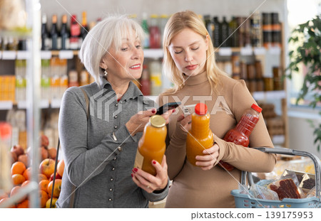 Girl and grandma scan QR code, take reading juice label using phone camera in shop Girl and grandma scan QR code, take reading juice label using phone camera in shop 139175953