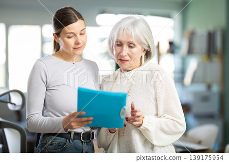 Woman shows elderly colleague documents Woman shows elderly colleague documents 139175954