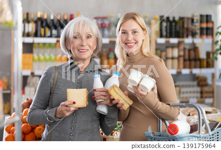 Girl and grandma with dairy products chooses something else, examines labels of cheese and yogurt 139175964