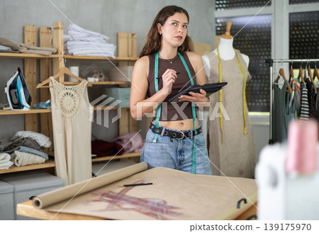 Tailor drawing fashion design on tablet in workshop Tailor drawing fashion design on tablet in workshop 139175970