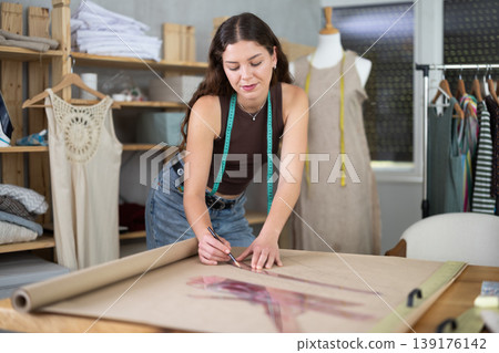 Female fashion designer drafting clothing pattern on paper in studio 139176142