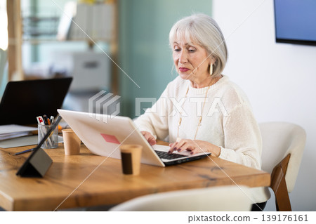 Elderly businesswoman, senior manager, work on laptop in modern company office Elderly businesswoman, senior manager, work on laptop in modern company office 139176161