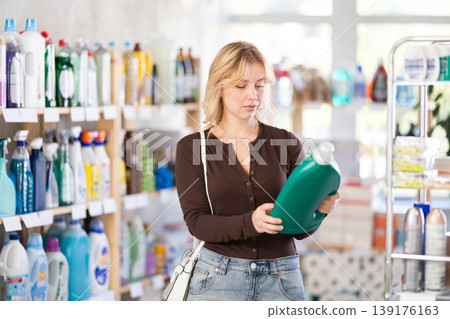 Young girl looking for household detergents on shelves in store Young girl looking for household detergents on shelves in store 139176163