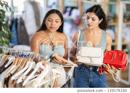 Two young women choosing dresses or tops and handbags 139176180