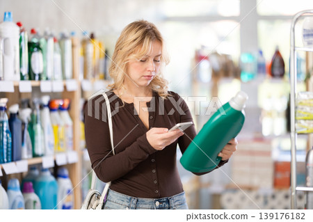 Before making purchase, girl buyer scan QR code on packaging of liquid detergent Before making purchase, girl buyer scan QR code on packaging of liquid detergent 139176182