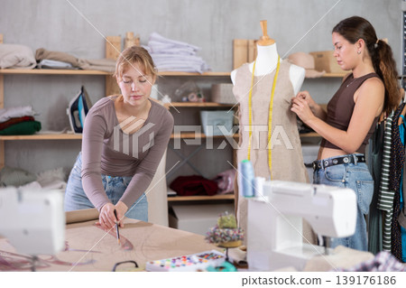 Women tailors design clothes and draw on paper in the workshop Women tailors design clothes and draw on paper in the workshop 139176186