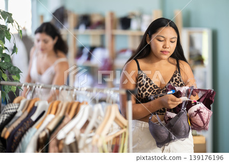 Young Latina chooses bras and underwear in the store Young Latina chooses bras and underwear in the store 139176196