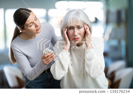 Adult woman sympathizes to sick senior female manager with headache and offers pain pills. Adult woman sympathizes to sick senior female manager with headache and offers pain pills. 139176234