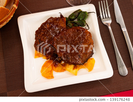 Veal roast with black sauce garnished by French fries and decorated baked green peppers. Veal roast with black sauce garnished by French fries and decorated baked green peppers. 139176248