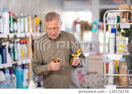 Man selects various tools - screwdrivers, pliers for repairs in supermarket Man selects various tools - screwdrivers, pliers for repairs in supermarket 139176256