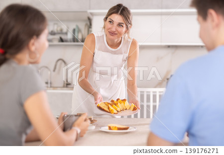 Woman talks casually with visitors and cuts pie for guests. Woman talks casually with visitors and cuts pie for guests. 139176271
