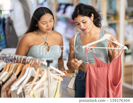 Two girls friends at trading floor pick out and buying sundress or tank top Two girls friends at trading floor pick out and buying sundress or tank top 139176304