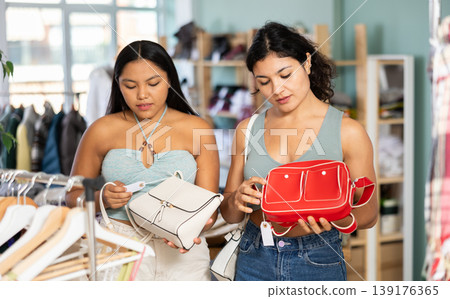 Two girls friends at trading floor pick out and buying handbag Two girls friends at trading floor pick out and buying handbag 139176365