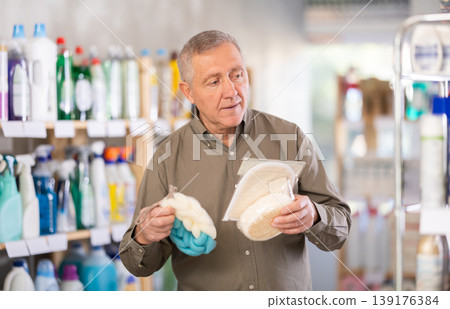 Elderly man buys shampoo, body wash and loofah in the household goods section of supermarket Elderly man buys shampoo, body wash and loofah in the household goods section of supermarket 139176384