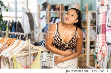 Female shopper suffers from headache while shopping at clothing store Female shopper suffers from headache while shopping at clothing store 139176401