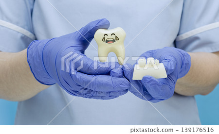 Dentist holding a sad crying tooth toy and jaw model, symbolizing toothache and dental problems. 139176516